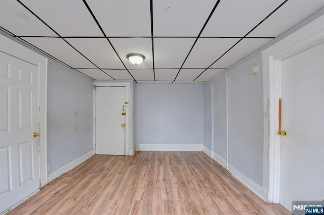 finished basement featuring baseboards, light wood-style floors, and a drop ceiling