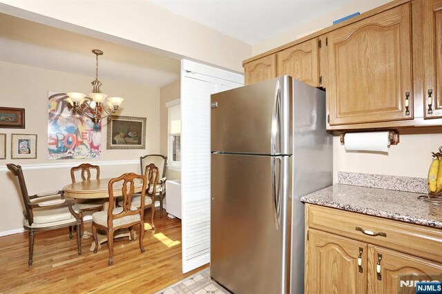 311 Grand Ave Unit 23, Englewood, NJ 07631 - kitchen featuring light stone countertops, an inviting chandelier, light wood-style flooring, freestanding refrigerator, and pendant lighting