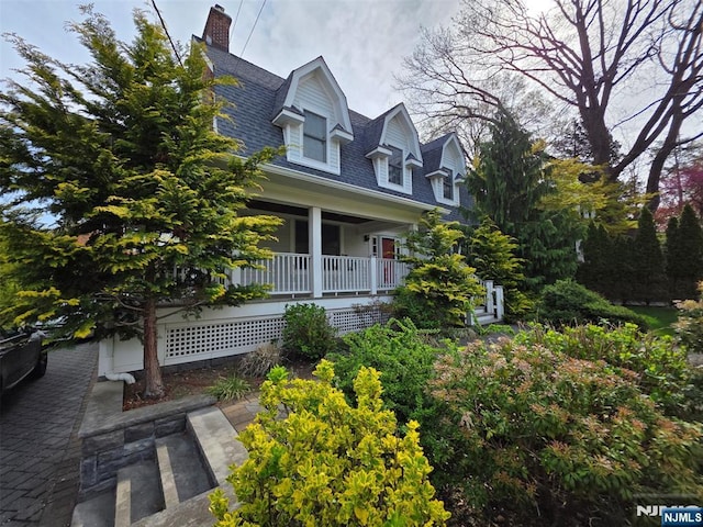 cape cod house with a shingled roof and covered porch
