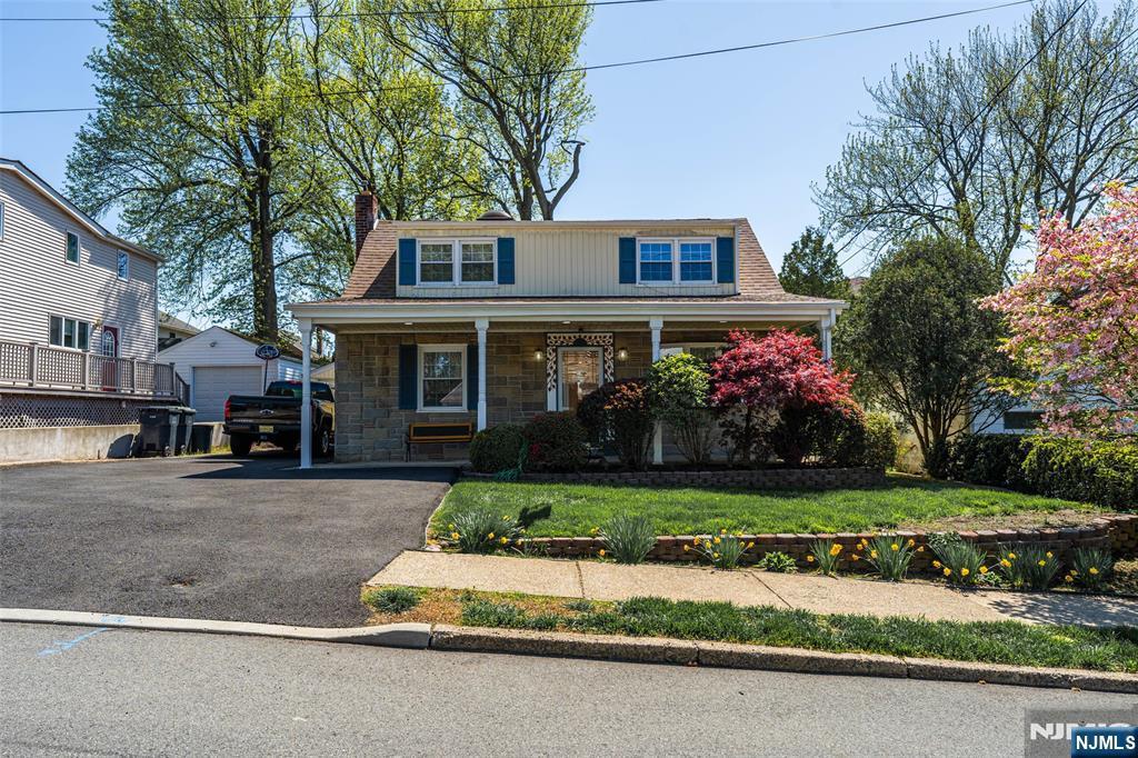12 Gordon Rd, Bergenfield, NJ 07621 - view of front of property with covered porch, stone siding, a chimney, an outbuilding, and a detached garage