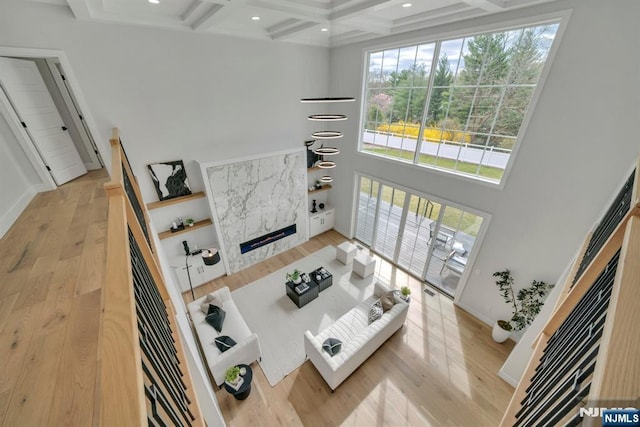 living room featuring light wood-type flooring, a towering ceiling, beamed ceiling, coffered ceiling, and recessed lighting