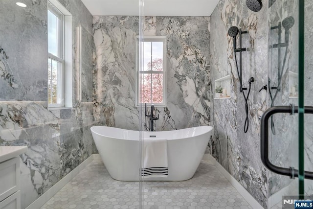 bathroom with a freestanding bath, vanity, a marble finish shower, and plenty of natural light