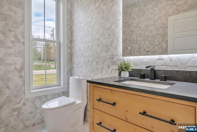 bathroom with toilet, tile walls, decorative backsplash, tile patterned flooring, and vanity