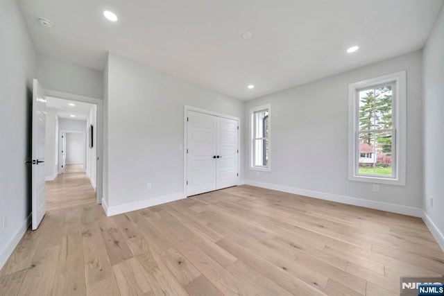 unfurnished bedroom with baseboards, recessed lighting, light wood-style floors, and a closet