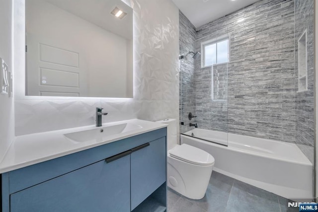 bathroom with toilet, tile walls, tile patterned flooring, vanity, and tub / shower combination