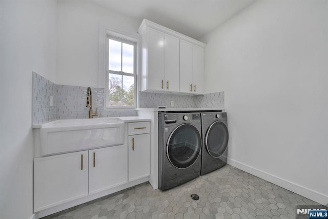 washroom featuring cabinet space, washing machine and dryer, baseboards, and a sink