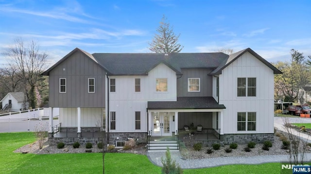 view of front of home with board and batten siding, a front lawn, covered porch, and fence