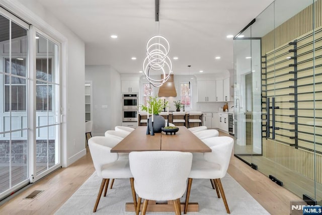 dining space with light wood finished floors, visible vents, recessed lighting, and a notable chandelier