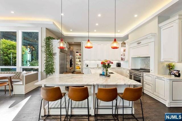 354 Hardenburgh Ave, Demarest, NJ 07627 - kitchen with premium appliances, white cabinetry, light stone countertops, a breakfast bar area, and recessed lighting
