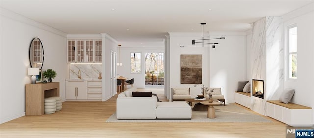 living room with crown molding, baseboards, and light wood-type flooring