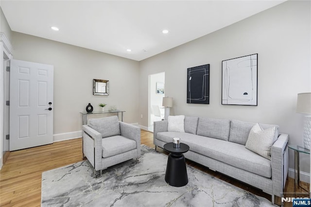 living area with baseboards, wood finished floors, and recessed lighting
