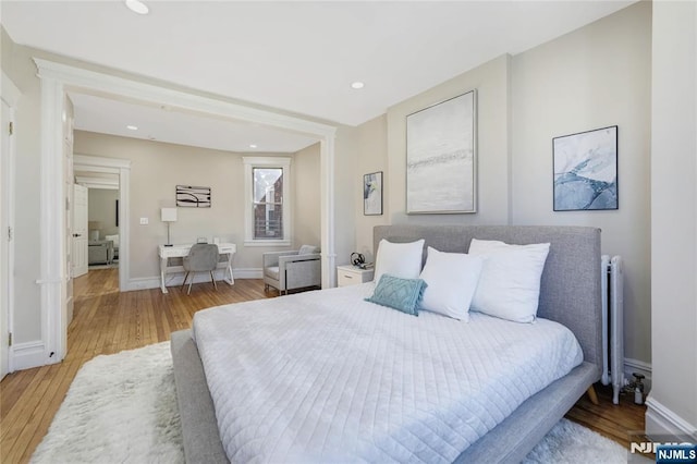 bedroom featuring radiator, light wood-style flooring, baseboards, and recessed lighting