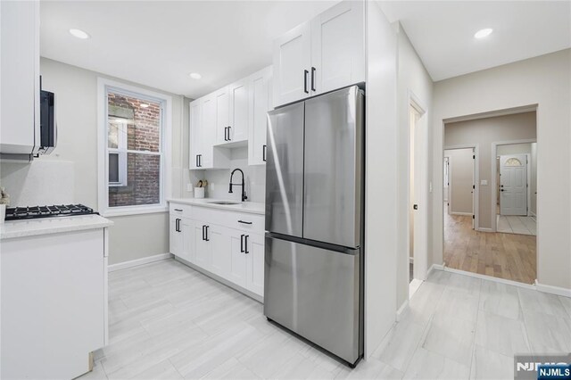kitchen with light countertops, white cabinets, appliances with stainless steel finishes, and a sink
