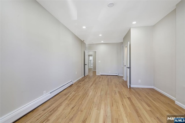 spare room featuring light wood-type flooring, baseboard heating, baseboards, and recessed lighting