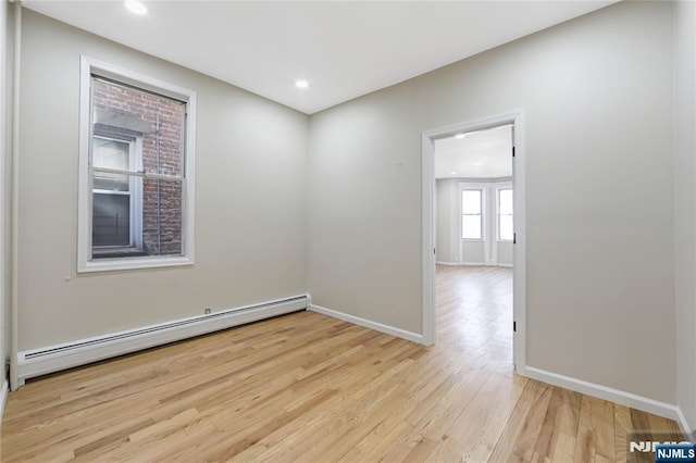 spare room featuring a baseboard radiator, light wood-type flooring, baseboards, and recessed lighting