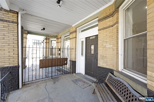 entrance to property with a porch and brick siding