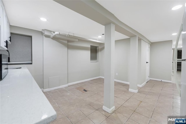 finished below grade area featuring baseboards, light tile patterned flooring, and recessed lighting