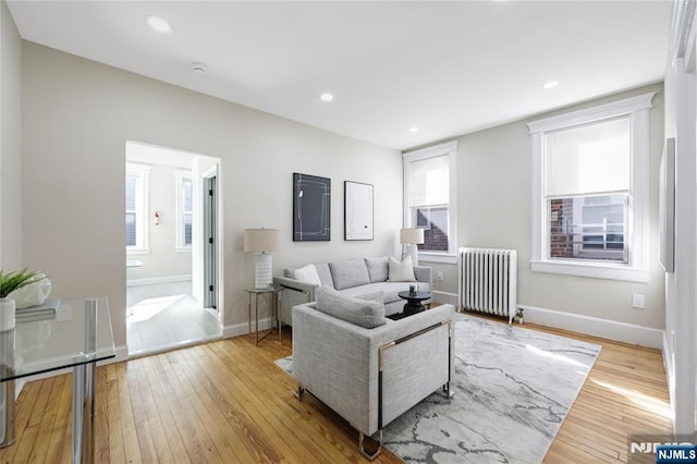 living room featuring light wood-type flooring, baseboards, recessed lighting, and radiator