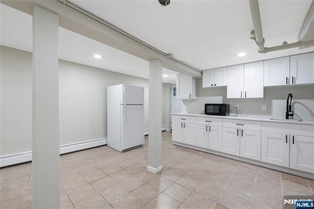 kitchen with white cabinets, light countertops, a sink, freestanding refrigerator, and black microwave