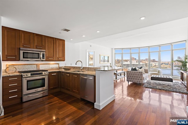 8100 River Rd Unit 1013, North Bergen, NJ 07047 - kitchen featuring appliances with stainless steel finishes, a sink, a peninsula, dark wood-style flooring, and expansive windows