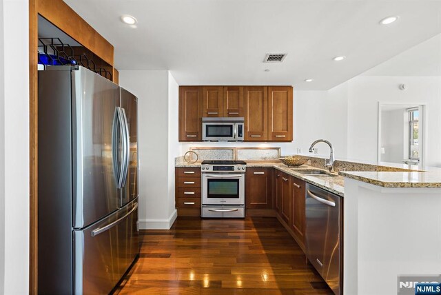 8100 River Rd Unit 1013, North Bergen, NJ 07047 - kitchen featuring stainless steel appliances, a sink, a peninsula, dark wood-style floors, and light stone countertops