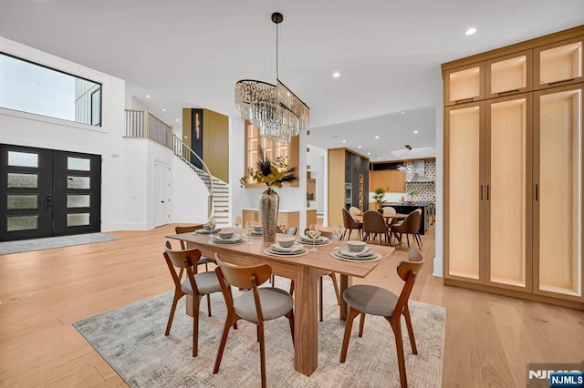 dining room featuring recessed lighting, light wood-style floors, stairway, and an inviting chandelier