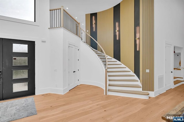foyer with visible vents, baseboards, wood finished floors, a high ceiling, and stairs