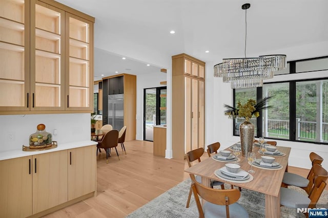 dining space with light wood finished floors, recessed lighting, and a notable chandelier