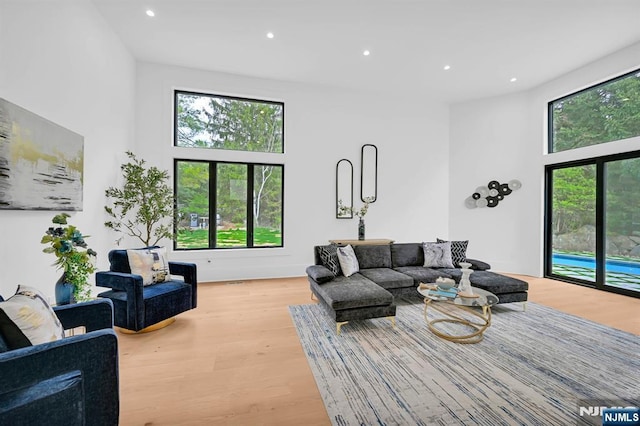 living room with a high ceiling, light wood finished floors, and recessed lighting