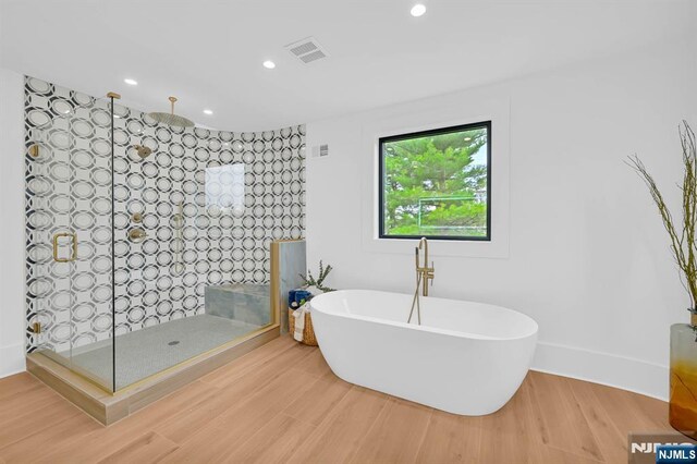 bathroom featuring recessed lighting, wood finished floors, visible vents, a walk in shower, and a freestanding tub