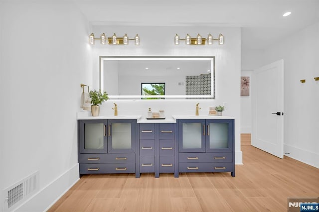 interior space featuring double vanity, wood finished floors, visible vents, and baseboards