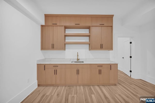 kitchen featuring light countertops, light wood-style flooring, baseboards, and a sink