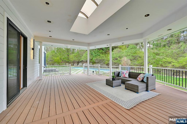 wooden deck with an outdoor hangout area and a fenced in pool
