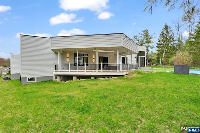 rear view of house featuring a wooden deck and a lawn