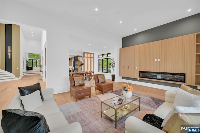 living area featuring a glass covered fireplace, recessed lighting, light wood-style floors, and a healthy amount of sunlight