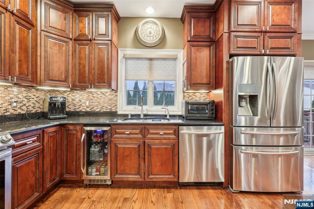 kitchen with tasteful backsplash, a sink, beverage cooler, a toaster, and stainless steel appliances