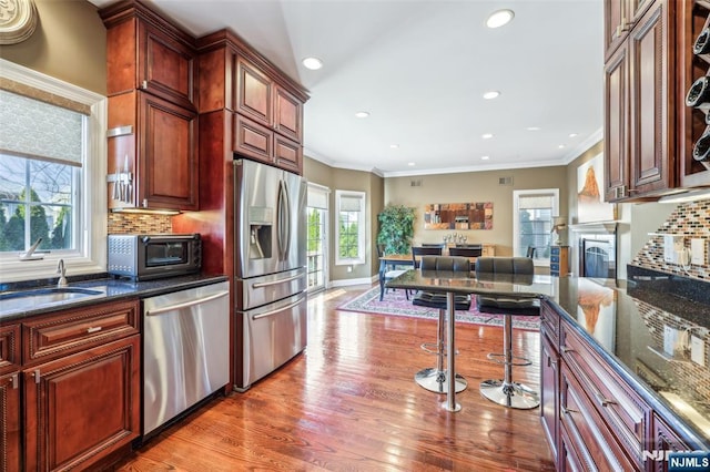 kitchen with stainless steel appliances, a sink, tasteful backsplash, recessed lighting, and light wood-style floors
