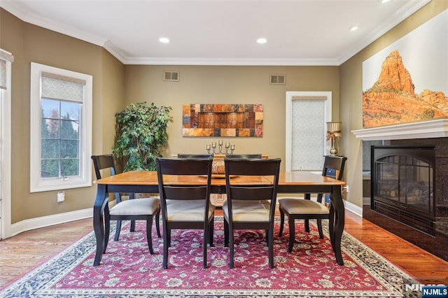dining area featuring wood finished floors, visible vents, and ornamental molding