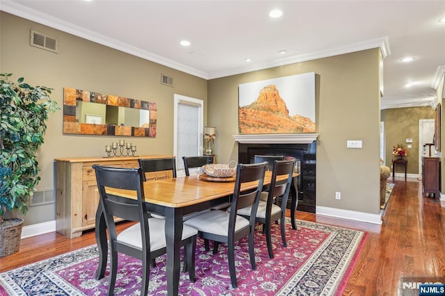 dining space with wood finished floors, visible vents, and ornamental molding