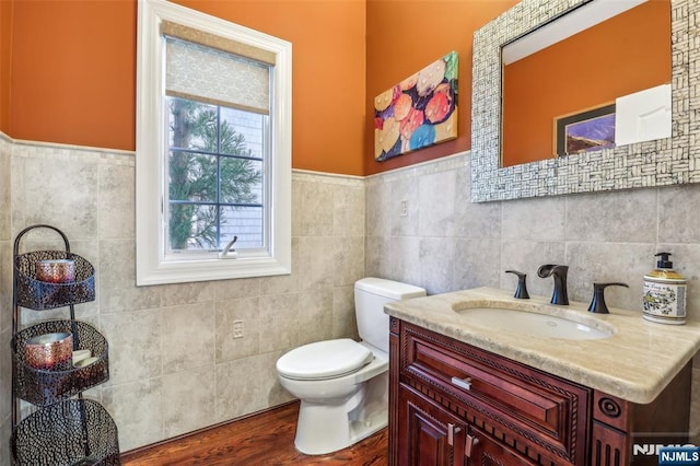 bathroom featuring tile walls, a wainscoted wall, vanity, and toilet