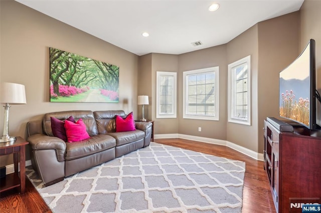 living area with baseboards, wood finished floors, visible vents, and recessed lighting