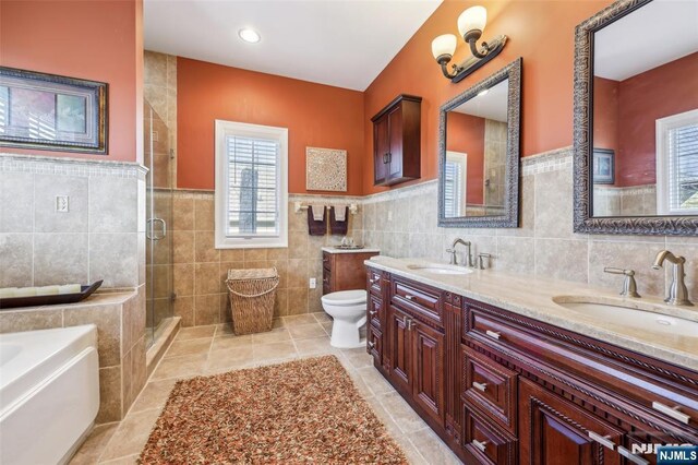 bathroom with tile walls, tile patterned floors, a sink, and toilet