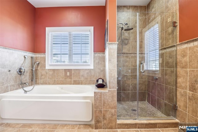 full bathroom featuring a bath, tile walls, and a stall shower