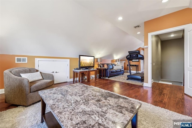 living room featuring vaulted ceiling, visible vents, and wood finished floors