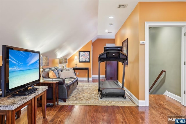 workout area with vaulted ceiling, wood finished floors, visible vents, and baseboards