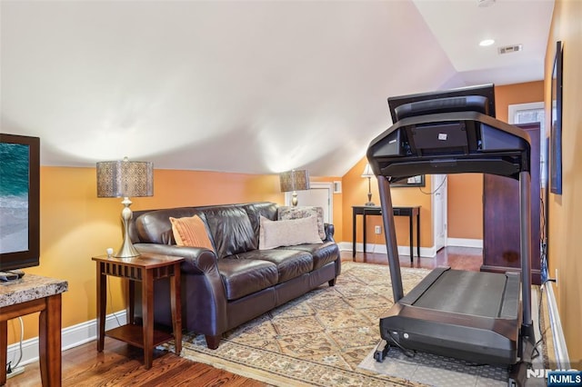 workout area with lofted ceiling, baseboards, wood finished floors, and visible vents