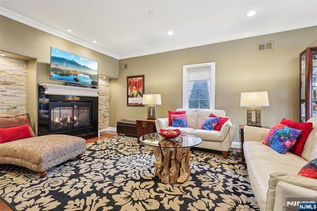 living room with a glass covered fireplace, visible vents, recessed lighting, and ornamental molding