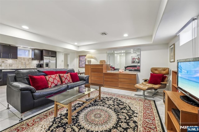 living room with visible vents, recessed lighting, and a raised ceiling