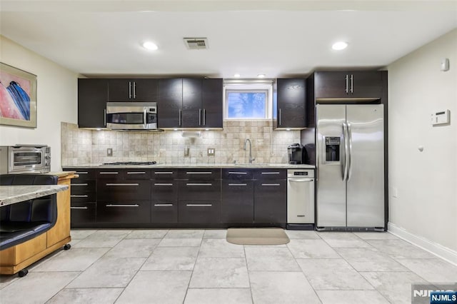 kitchen with a sink, decorative backsplash, a toaster, appliances with stainless steel finishes, and visible vents