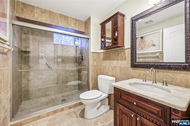 full bath with toilet, tile walls, a stall shower, visible vents, and vanity